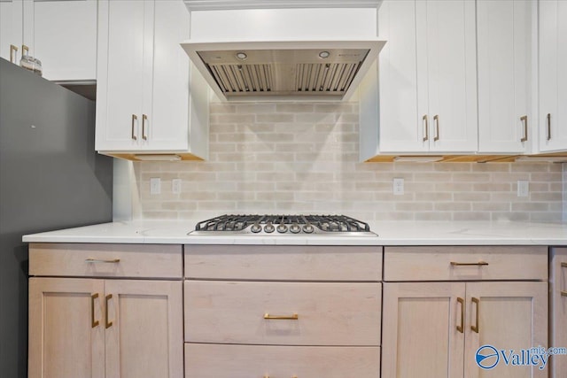 kitchen with decorative backsplash, custom exhaust hood, stainless steel gas cooktop, light stone counters, and light brown cabinets