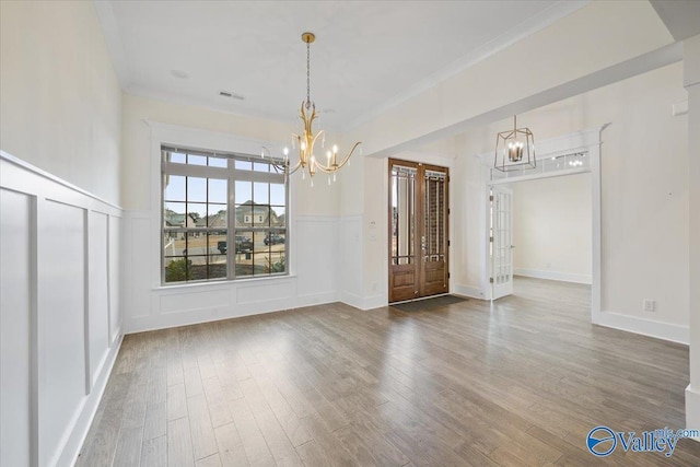 unfurnished dining area featuring hardwood / wood-style flooring, ornamental molding, and a chandelier