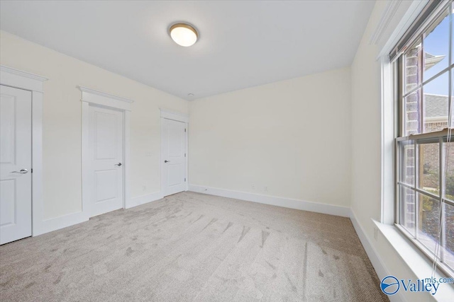 unfurnished bedroom with multiple windows and light carpet