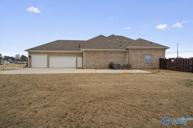 exterior space with central AC unit, a garage, and a lawn