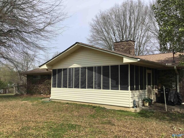 view of side of home featuring a sunroom and a yard