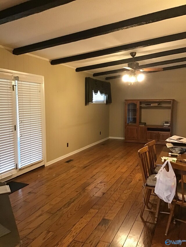 interior space featuring ceiling fan, dark wood-type flooring, and beamed ceiling