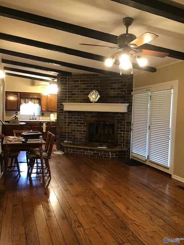 living room with dark hardwood / wood-style flooring, beam ceiling, a fireplace, and ceiling fan