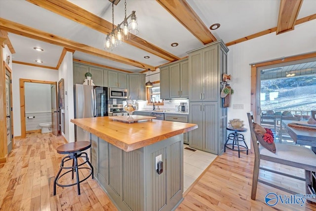 kitchen with stainless steel appliances, butcher block countertops, beam ceiling, and green cabinetry