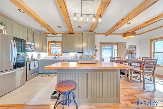 kitchen with appliances with stainless steel finishes, butcher block counters, a healthy amount of sunlight, and decorative backsplash