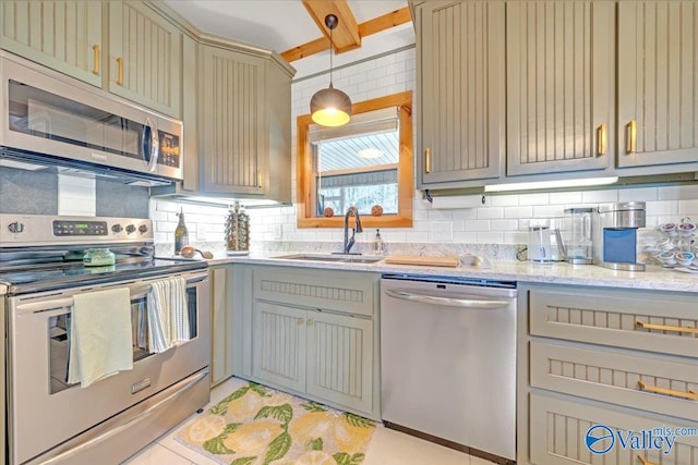 kitchen with appliances with stainless steel finishes, a sink, light stone countertops, gray cabinets, and backsplash