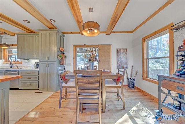 dining space with light wood-type flooring, beam ceiling, and baseboards