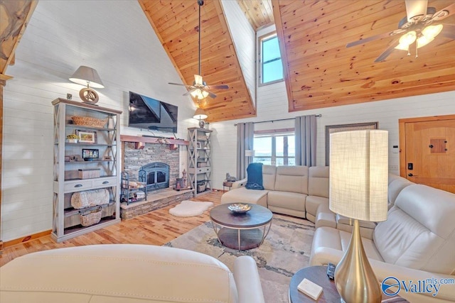 living room with wooden ceiling, a ceiling fan, wood finished floors, and a stone fireplace