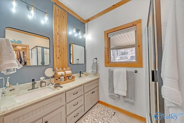 full bath with double vanity, a stall shower, baseboards, and a sink