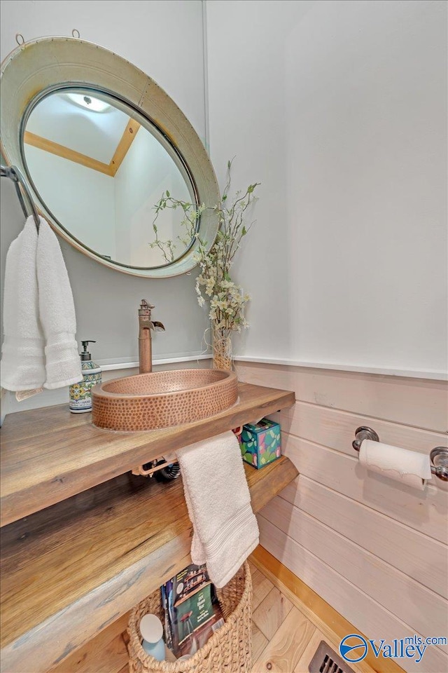 bathroom with wood finished floors and wainscoting