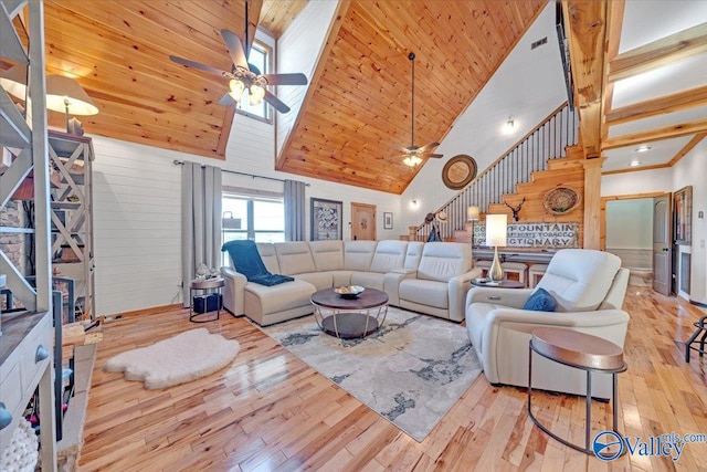 living area featuring hardwood / wood-style flooring, wood ceiling, ceiling fan, stairs, and a high ceiling