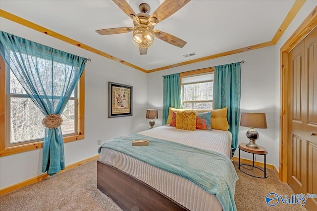 carpeted bedroom with baseboards, a ceiling fan, visible vents, and crown molding