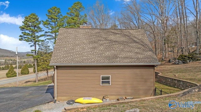 view of side of home featuring roof with shingles, a mountain view, and a chimney