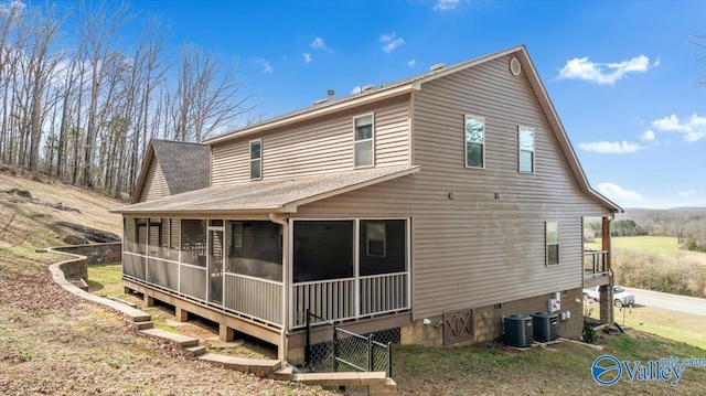 rear view of house featuring a shingled roof, cooling unit, and a sunroom