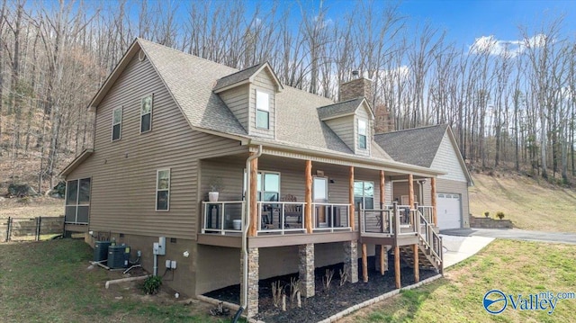 view of side of property with roof with shingles, a chimney, a porch, a lawn, and driveway