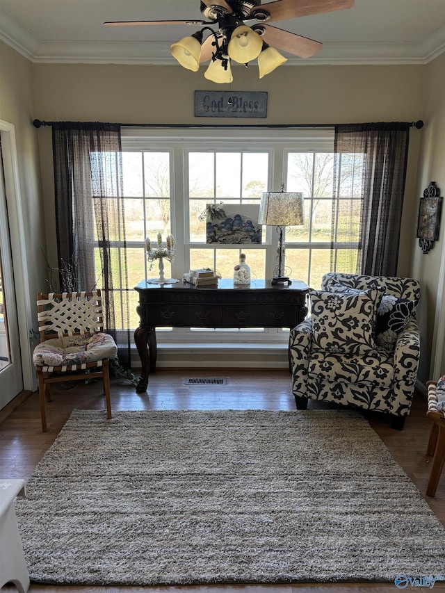sitting room featuring wood finished floors, visible vents, crown molding, and a ceiling fan