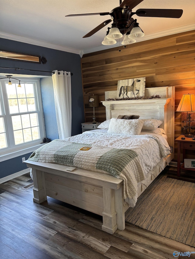 bedroom featuring crown molding, wood finished floors, wooden walls, ceiling fan, and baseboards