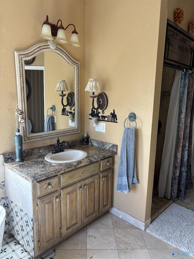 full bathroom featuring vanity, a textured wall, baseboards, tile patterned flooring, and a shower with shower curtain