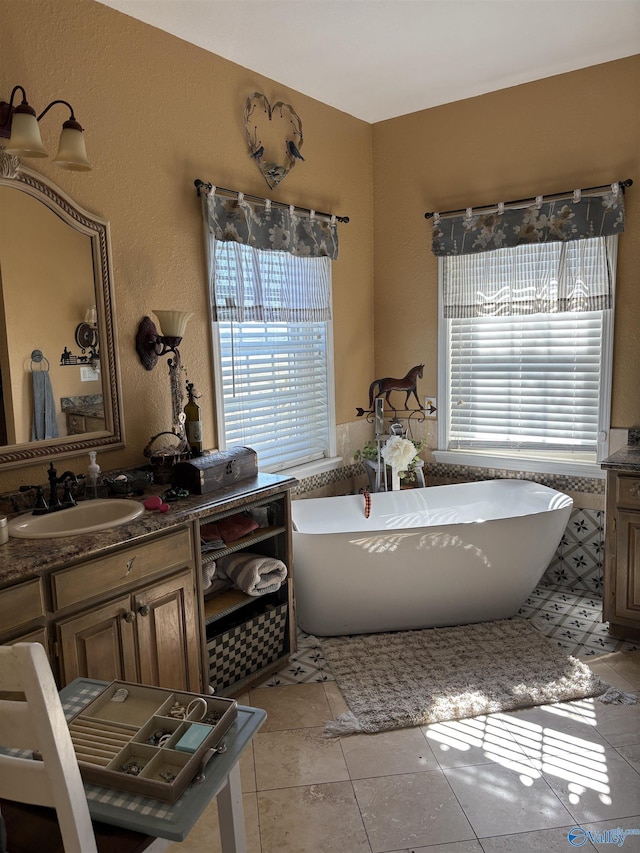 bathroom featuring a freestanding bath, tile patterned flooring, and vanity