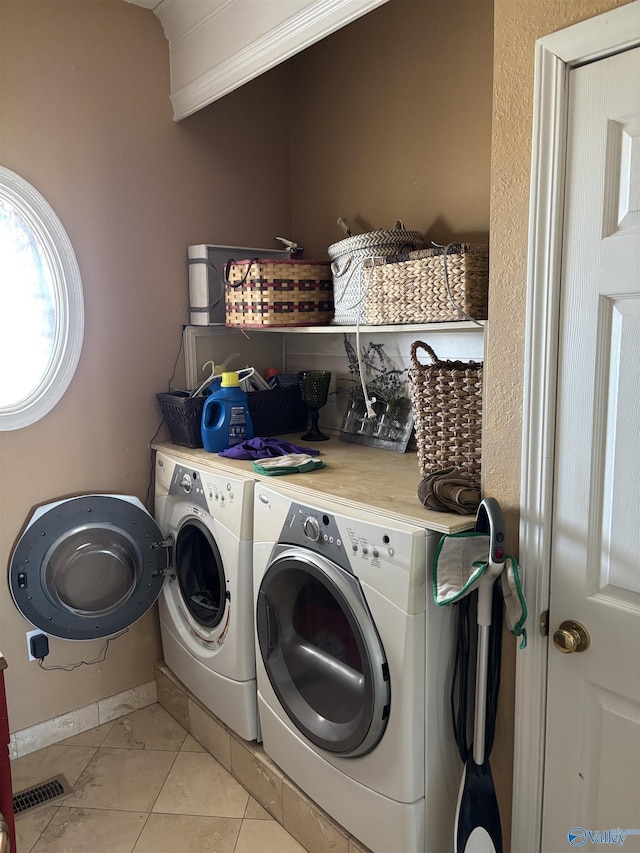 laundry area featuring washer and clothes dryer, light tile patterned floors, laundry area, baseboards, and visible vents