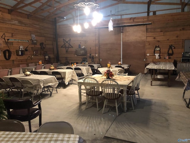 dining space with concrete flooring, lofted ceiling, and wood walls