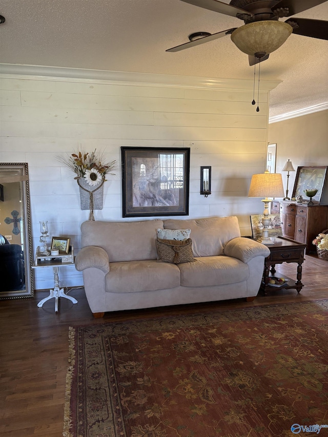 living room with a ceiling fan, wood finished floors, a textured ceiling, and ornamental molding