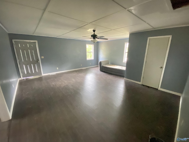 interior space with a ceiling fan, a paneled ceiling, baseboards, and wood finished floors