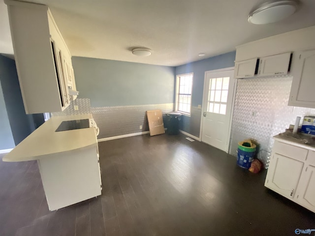 kitchen with dark wood-type flooring, light countertops, white cabinets, and a wainscoted wall