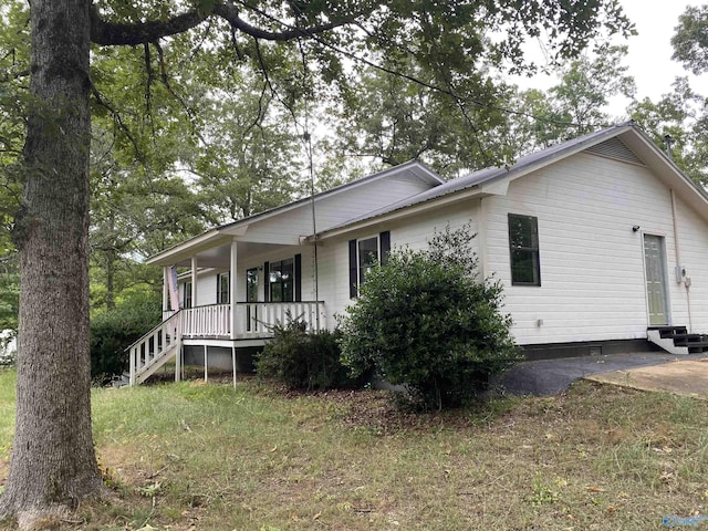 view of side of home featuring covered porch and metal roof