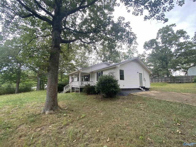 exterior space featuring driveway, covered porch, fence, and a front lawn