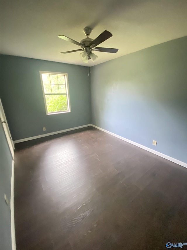 spare room featuring dark wood-type flooring, baseboards, and a ceiling fan