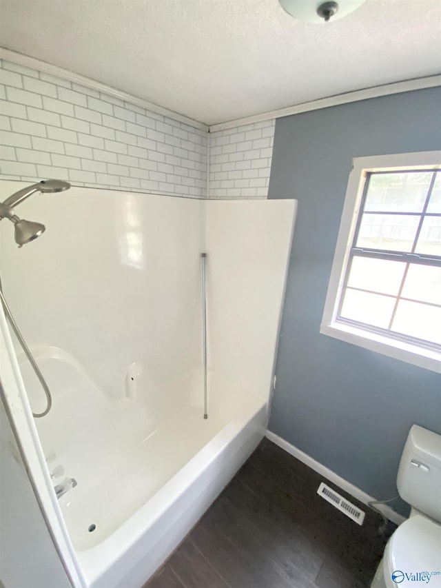 full bathroom featuring visible vents, toilet, a textured ceiling, wood finished floors, and walk in shower