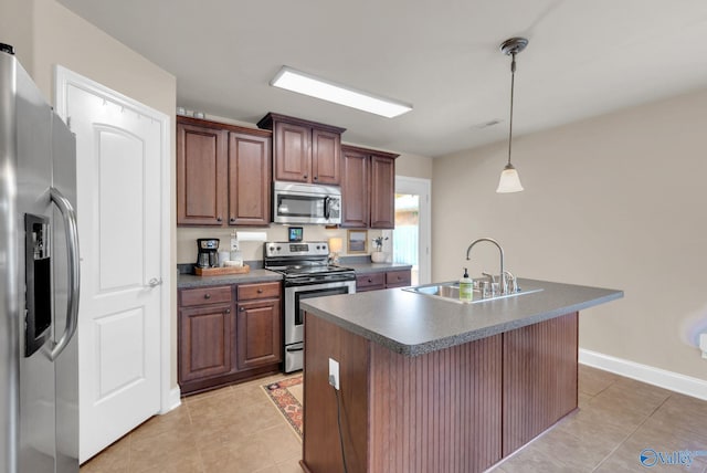 2626 SW Ashtynn Pl, Huntsville, AL 35803 - kitchen featuring stainless steel appliances, dark countertops, light tile patterned floors, hanging light fixtures, and an island with sink