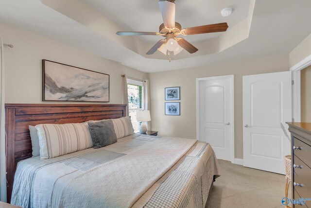 2626 SW Ashtynn Pl, Huntsville, AL 35803 - bedroom featuring a tray ceiling, light carpet, and a ceiling fan