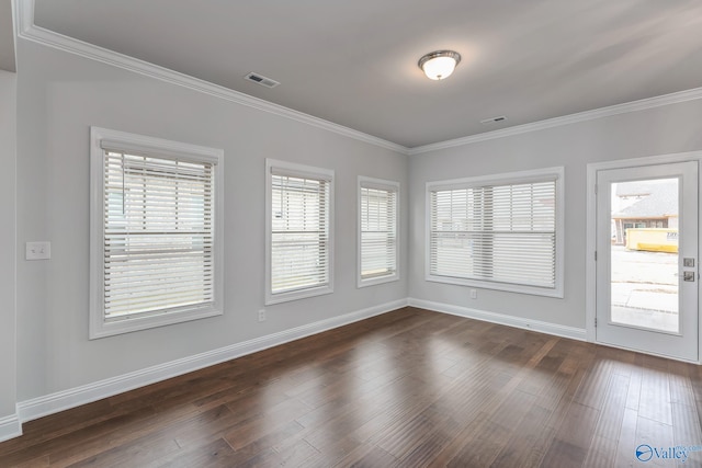 spare room with ornamental molding, plenty of natural light, and dark hardwood / wood-style floors