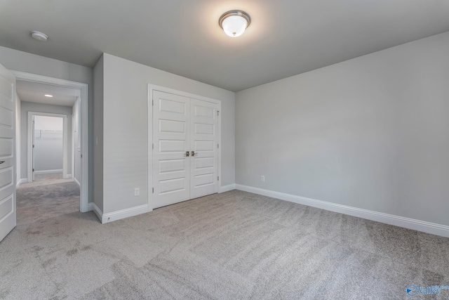 unfurnished bedroom with a closet and light colored carpet