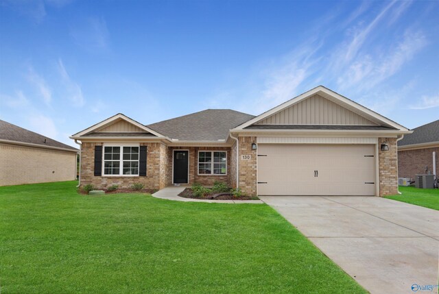 craftsman-style house featuring cooling unit, a garage, and a front lawn