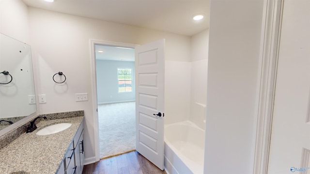 bathroom featuring wood-type flooring, bathtub / shower combination, and vanity