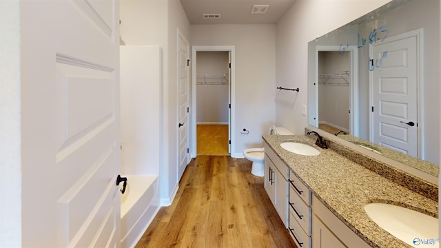 bathroom featuring vanity, hardwood / wood-style floors, a washtub, and toilet