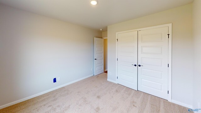 unfurnished bedroom featuring a closet and light colored carpet