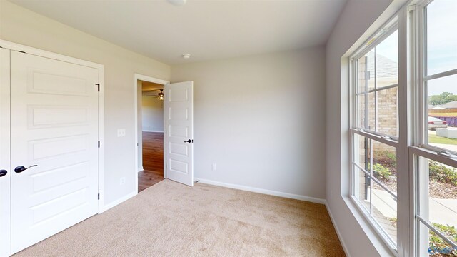 unfurnished bedroom with multiple windows, a closet, and carpet flooring