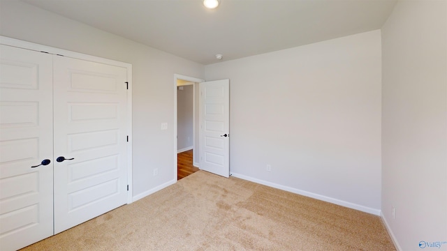 unfurnished bedroom with light colored carpet and a closet