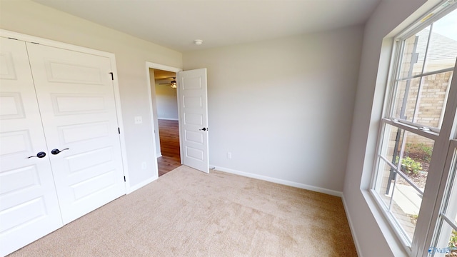 unfurnished bedroom with light carpet and a closet