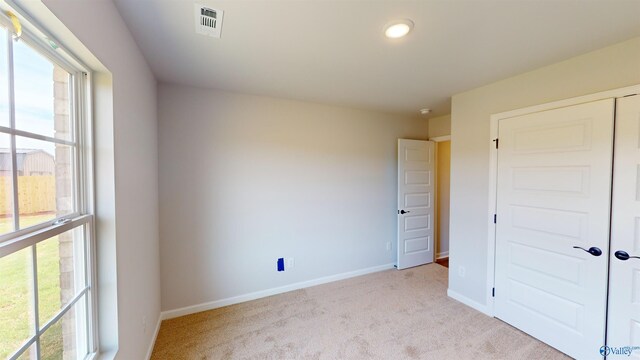 unfurnished bedroom with light colored carpet and a closet