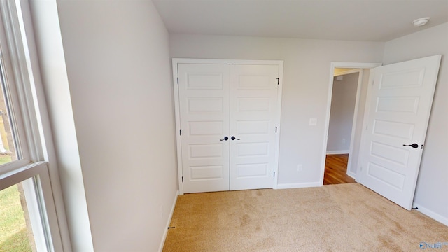 unfurnished bedroom featuring light carpet and a closet