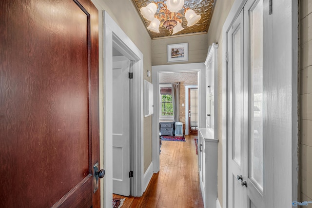 hallway with light wood-type flooring and an inviting chandelier