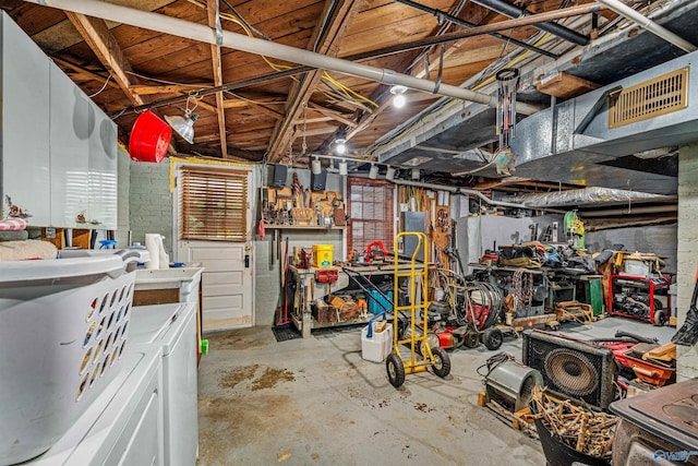 unfinished basement with visible vents, a workshop area, and washer and clothes dryer