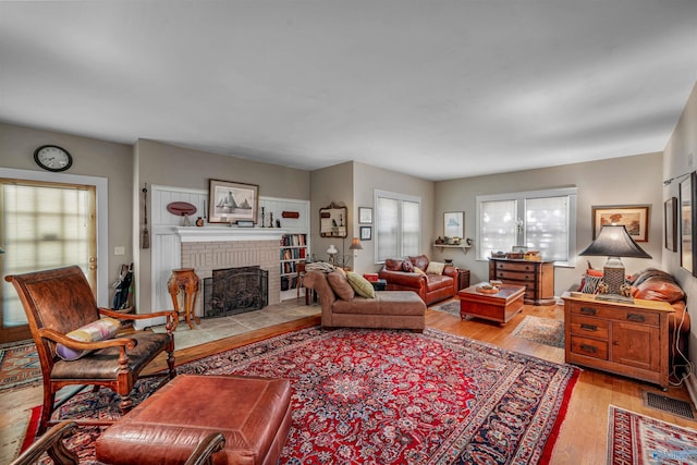 living room featuring a brick fireplace and light wood finished floors