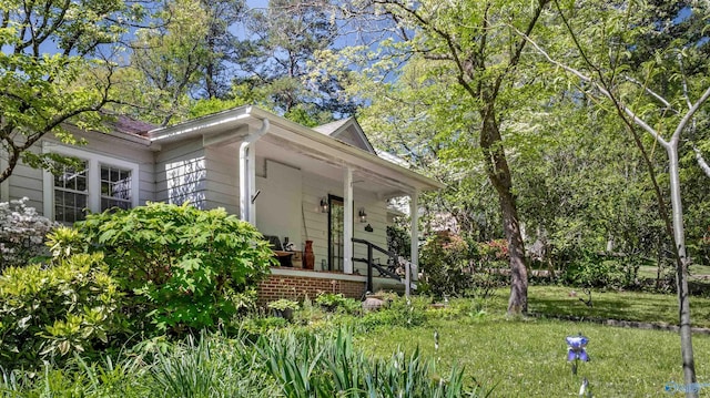 view of side of home featuring a porch and a yard