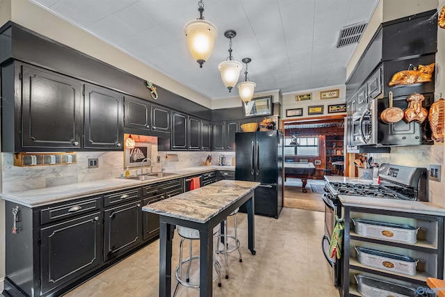kitchen featuring dark cabinets, visible vents, a sink, and appliances with stainless steel finishes
